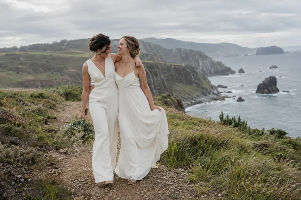 Imagen ilustrativa generada: Dos novias se abrazan junto a la costa